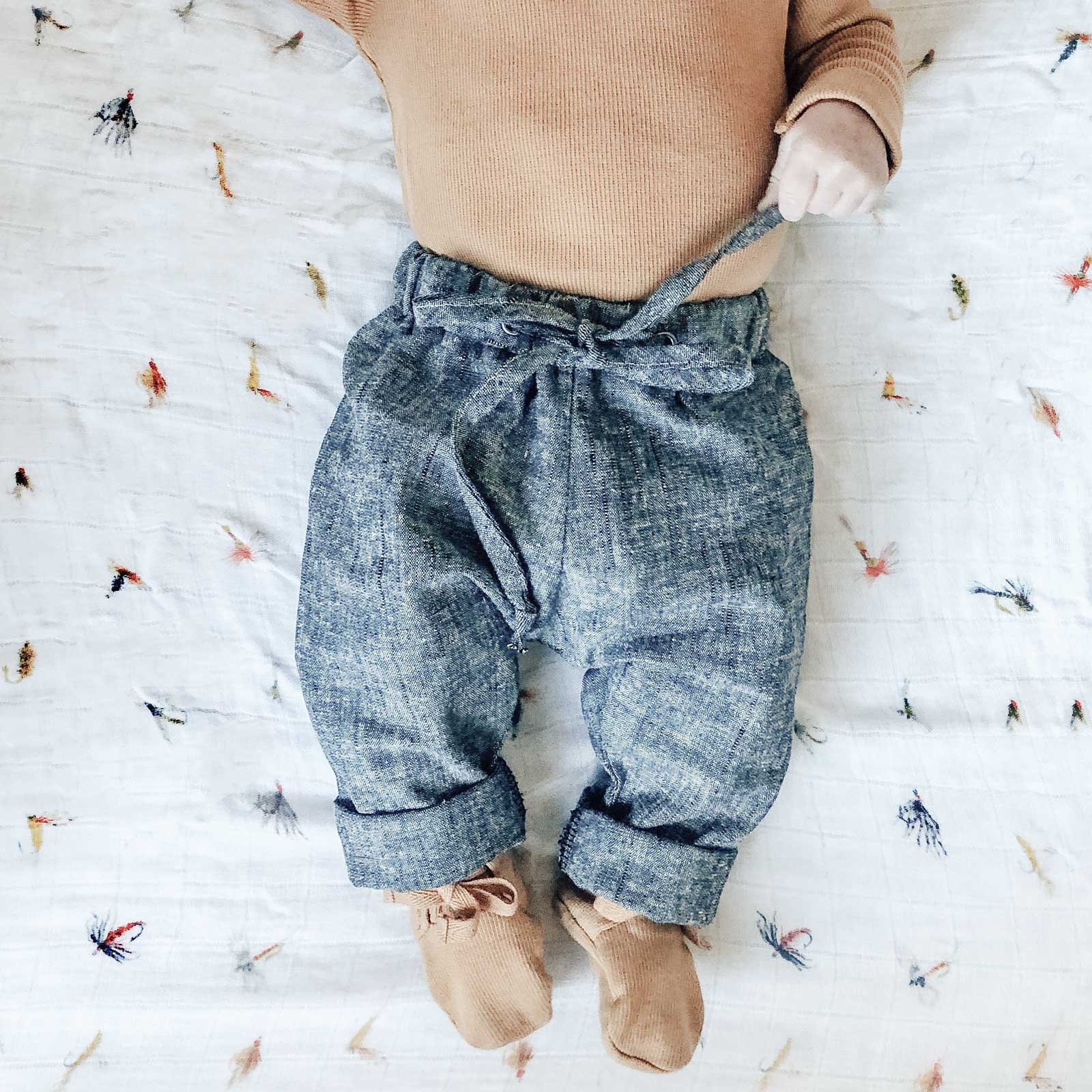 baby boy lying on muslin sheets wearing Beya Made linen pants