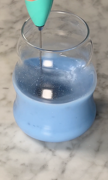 blue spirulina powder being whisked with oat milk creamer