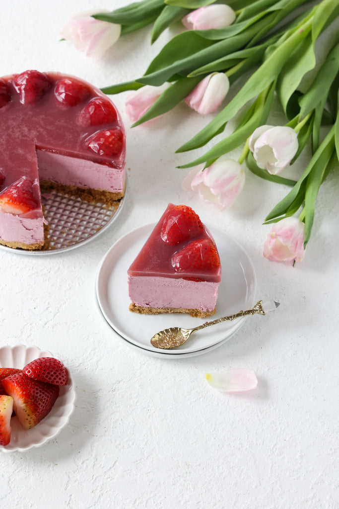 strawberry cheesecake and plated slice next to tulips