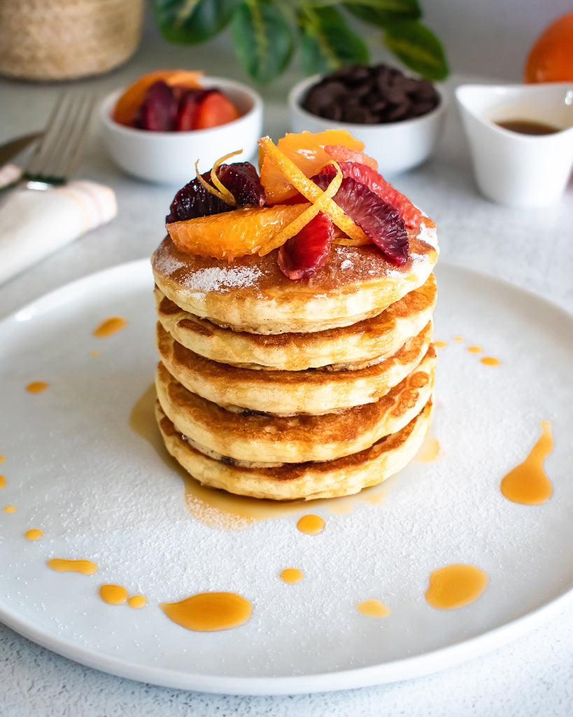 stack of pancakes topped with citrus sections