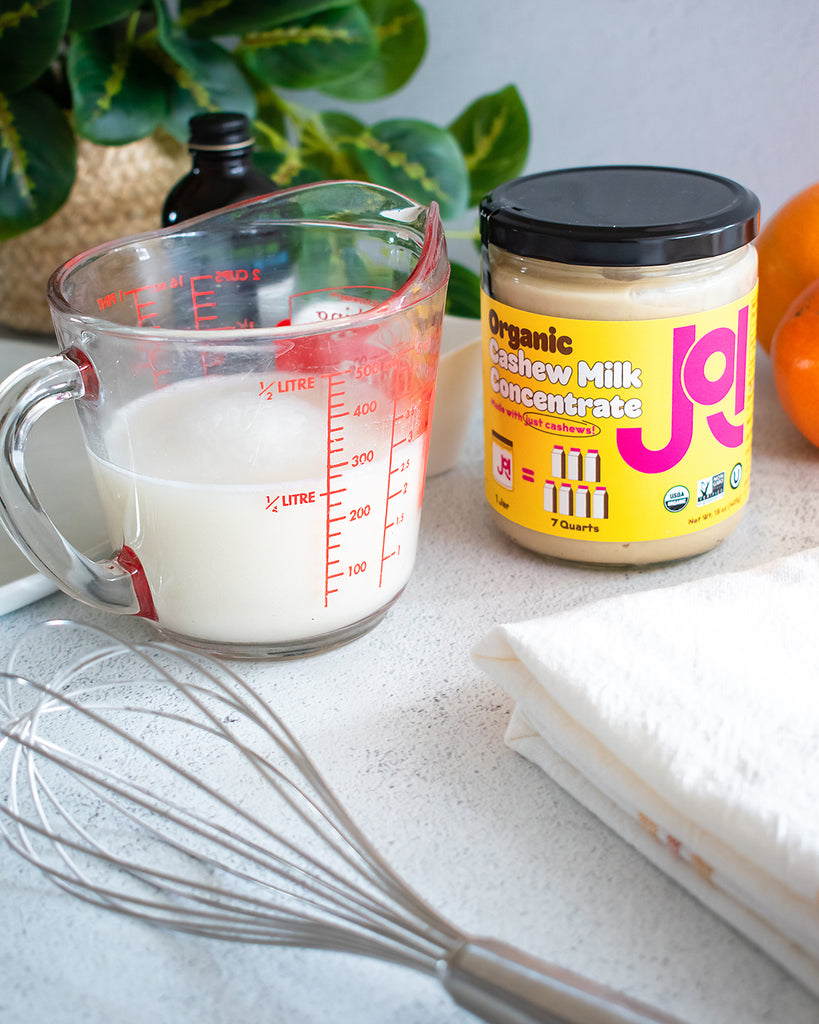 measuring cup filled with milk next to a jar of JOI and a metal whisk