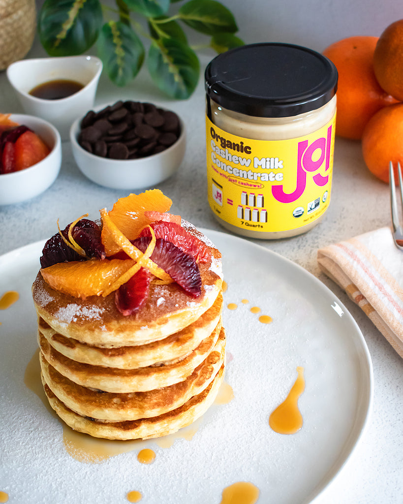 Stack of pancakes topped with citrus and JOI jar to the side