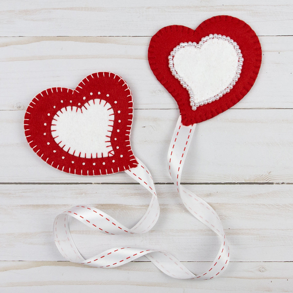Two red and white felt hearts attached by a red and white ribbon