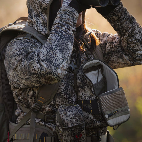 female hunter looking through binoculars