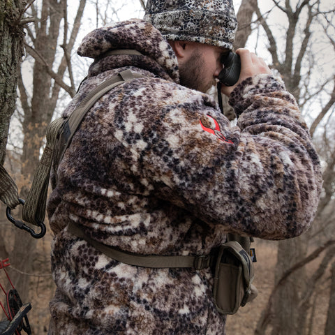 male hunter on tree stand, looking through binoculars