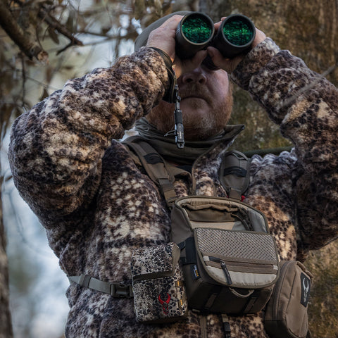 man looking through binoculars on a hunt