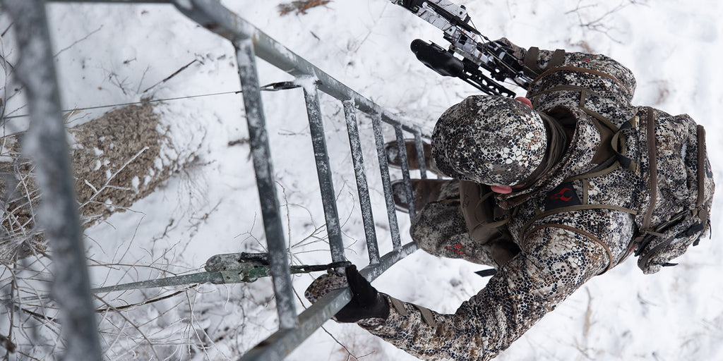 man climbing up tree stand during winter hunt