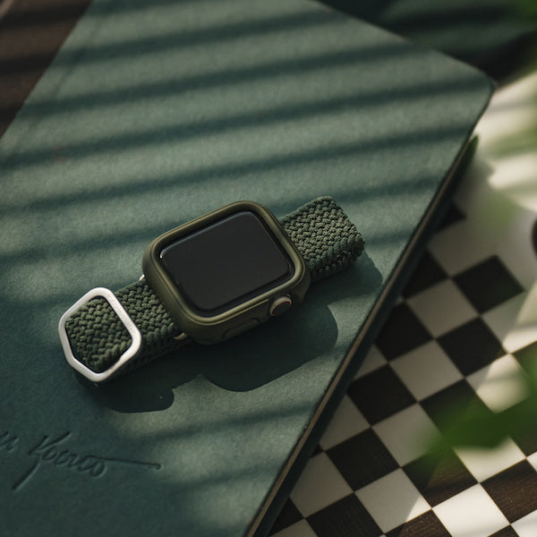 グリーンのApple Watch ケースとブレイデッドバンドが装着されたApple Watchがグリーンの本の上に置いてある