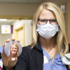 Nurse wearing a mask and holding a photo button of herself