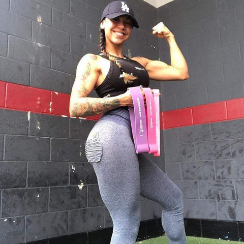 Woman flexing while holding pieces of the Hunnybuns Workout Kit