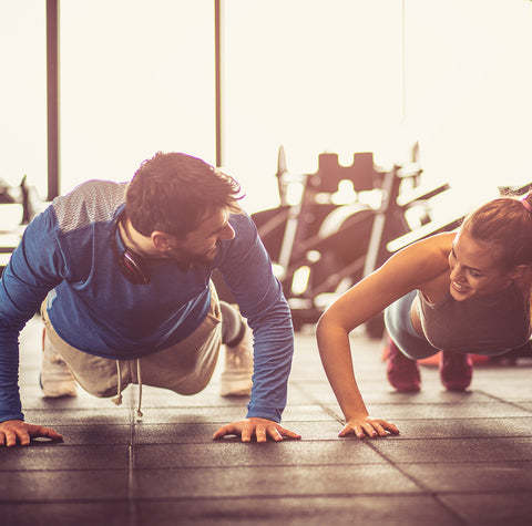 Man and woman in a gym, each in push-up position
