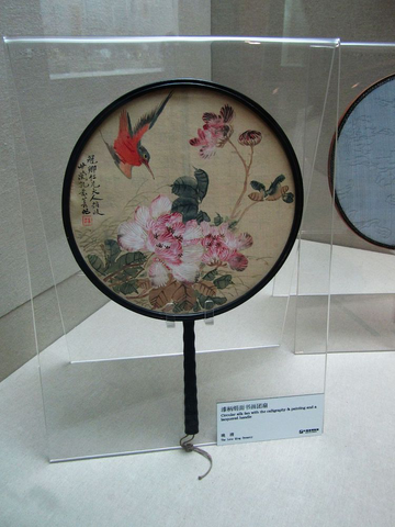A circular silk fan with calligraphy, painting, and a lacquered handle, a courtesy of WikiMedia Commons.