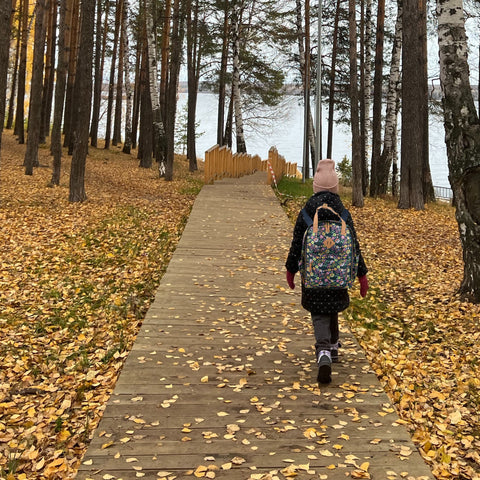 a young girl wearing a backpack walking outdoors