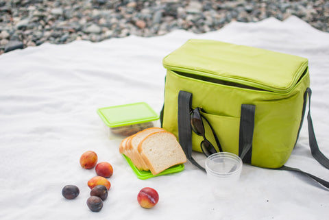 An insulated lunch bag with a picnic lunch on a white blanket