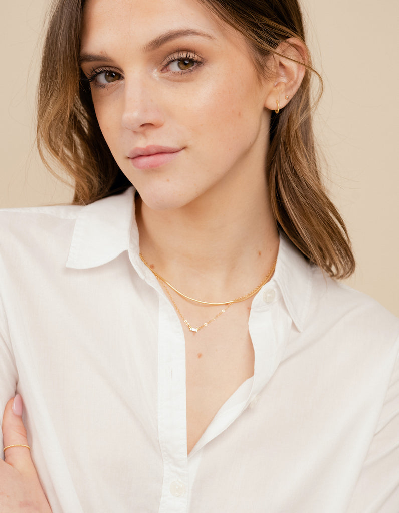 Close-up of a model in a casual white shirt wearing a pair of the dainty gold, nickel-free Beaded Hoop Studs by Katie Dean Jewelry, illustrating their versatility and classic appeal.