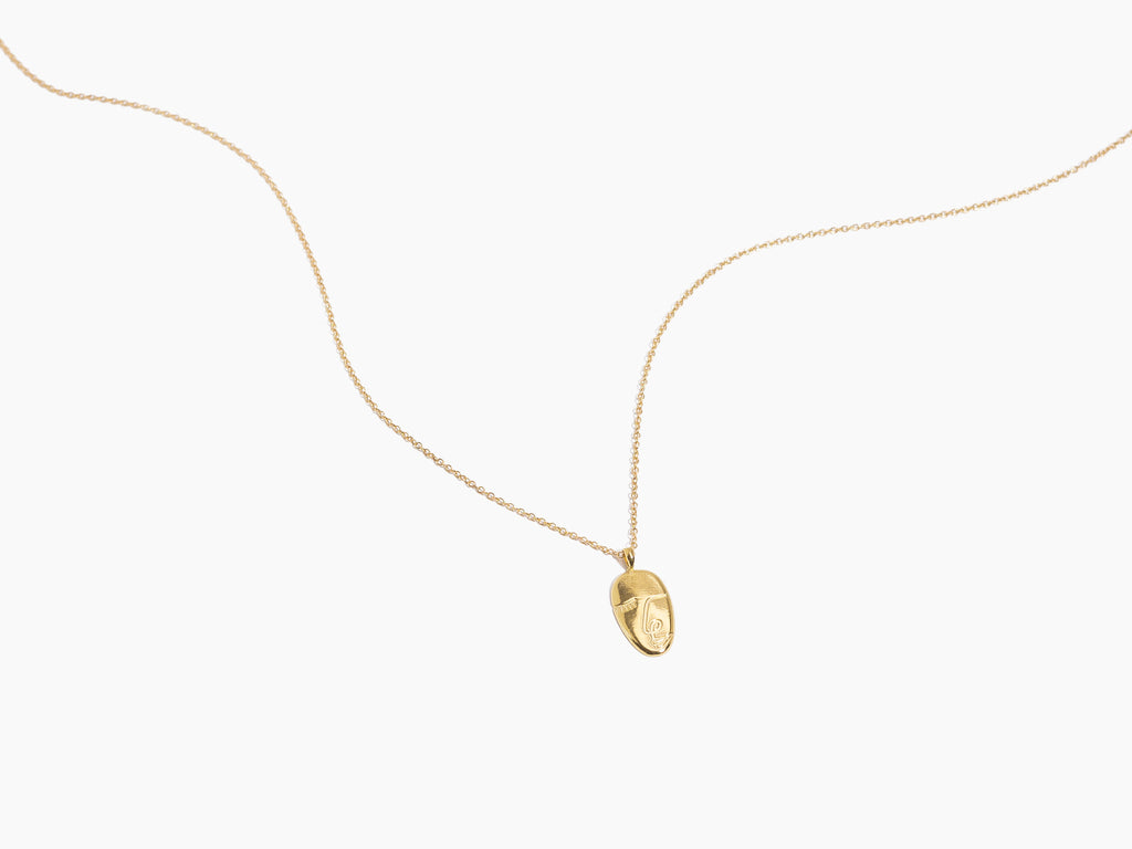 Close-up of Katie Dean Jewelry Artist Face Necklace with sleek gold pendant on a delicate chain.