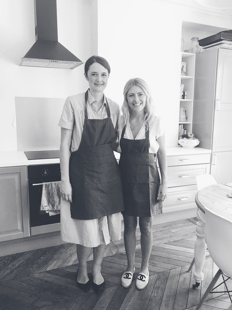 Katie Dean with Benedicte, owner of The Parisian Kitchen, wearing aprons in her Paris Kitchen.