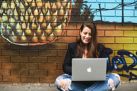 Women sitting infront of street art wall working on a laptop