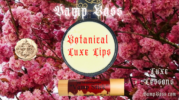 Cherry blossoms in beautiful reddish pinks are in the background with a container of White body butter cream centered like the moon. The words state: Botanical Luxe Lips and Luxe Lessons with Vamp Boss. An eco friendly lip balm packaged in bamboo is on the right with colorful vintage style label that says: Vamp Stick. The best lip balm for luxury lips. no synthetics, no parabans, no petroleum.