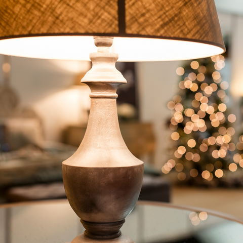 Lamp sitting in front of a christmas tree in the background