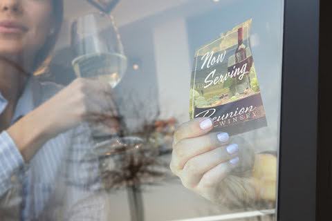 woman applying a window cling while another woman drinks wine