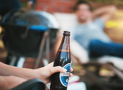 holding brown beer bottle at a barbeque