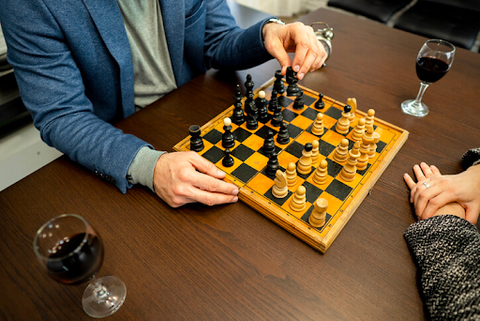 formally dressed people playing chess with wine