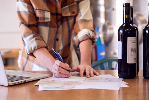 signing papers next to wine bottle