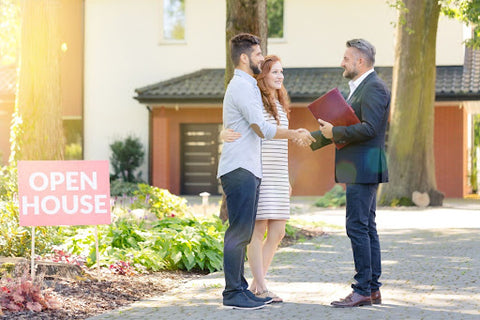 realtor shaking hands with couple outside of home