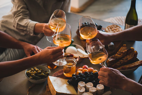 tapping wine glasses around a charcuterie board