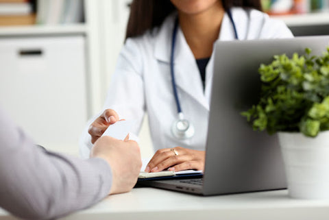 doctor with laptop handing patient piece of paper