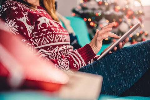woman in christmas sweater using tablet