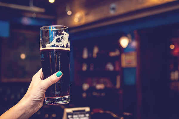 raising a glass of dark beer in a pub