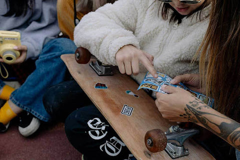 girl applying stickers on skateboard