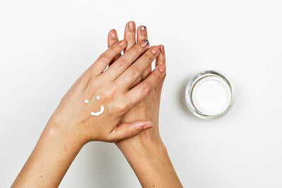 Two hands with lotion in smiley face design.