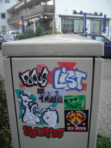 Stickers on a trash bin outside.