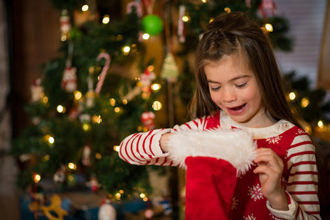 Child looking in christmas stocking with decorated tree in background