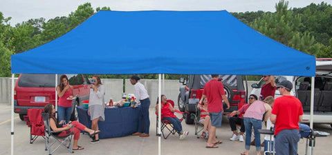 Blue canopy tent in parking lot with people underneath.