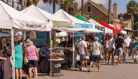 Busy farmers market with canopy tent stands.