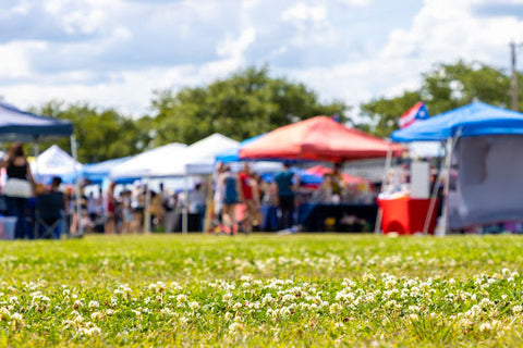 Blurred canopy tents in a field for an event.