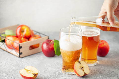 apple cider poured into glasses with box of apples in the background