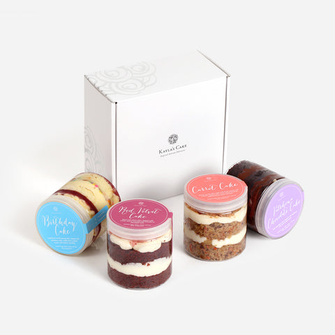 Containers of layered cake in front of a box.