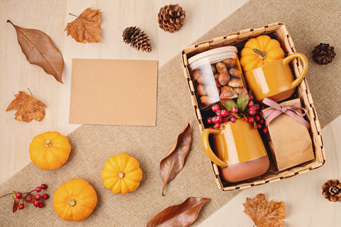 Fall-themed table with pumpkins, leaves, pine cones, and a basket of Autumn gifts