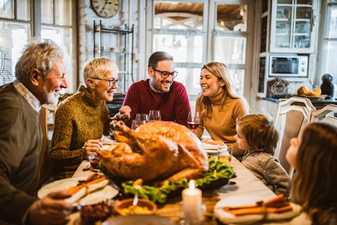 Family smiling, sitting around Thanksgiving dinner table