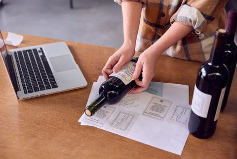 Woman applying label to wine bottle