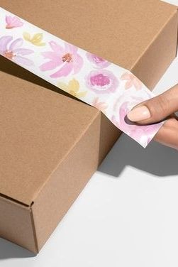 Hand putting custom packaging tape on box.