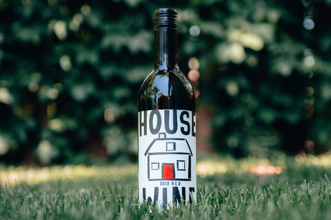 House Wine red bottle on grass.