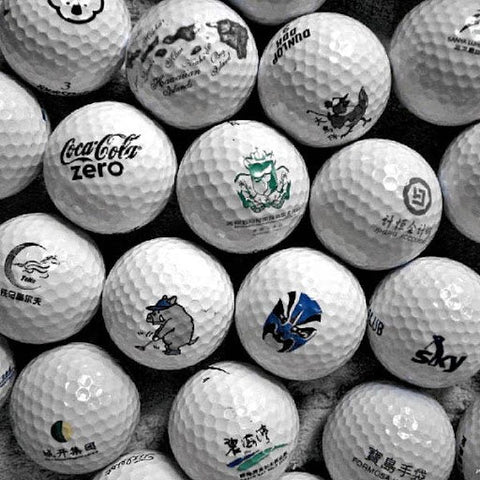 Pile of white golf balls with different logos.