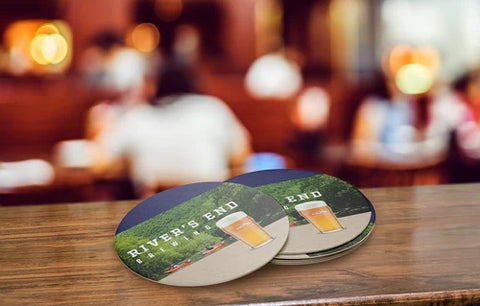 River's End Brewing custom coasters on a wood counter.