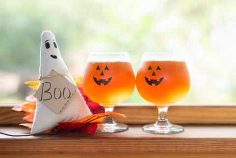 Two Halloween beers next to a ghost doll on a table